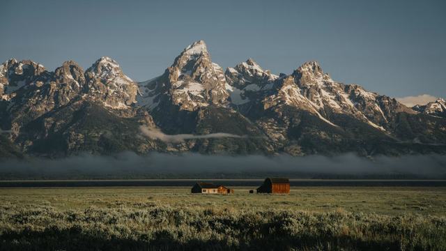 The Grand Tetons at dawn with an old barn in the sagebrush